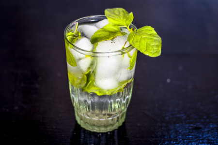Fresh mint water with ice cubes on a black wooden surface with fresh organic mint leaves.の写真素材
