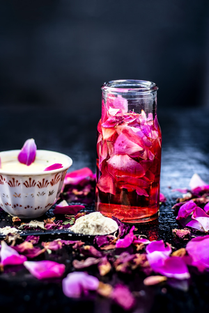 Close up of ayurvedic and beneficial face pack for dull and black skin i.e. Face pack of Rose water with gram flour and some rosa petals on wooden surface.の写真素材