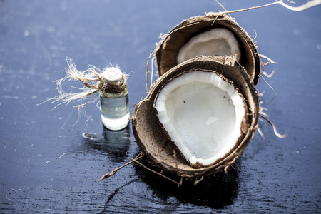 Close up of raw organic coconut or Cocos nucifera with its essence in a transparent bottle used in many Indian and Asian flavored beverages and in cold drinks and sherbats.の写真素材