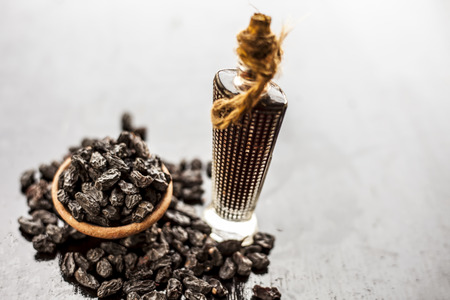 Dry fruit essence of Black raisin or Kali kishmish or black currant or Zante currant in a transparent bottle on wooden surface used in flavored Indian and Asian beverages.の写真素材