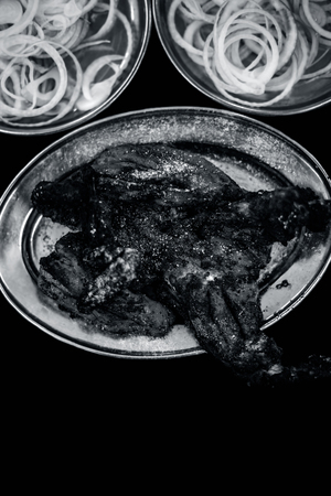 Indian and Asian lunch and dinner dish âTandoori Chickenâ a dish prepared with marinated chicken roasted and served with fresh roundly sliced onions and lemons.の写真素材