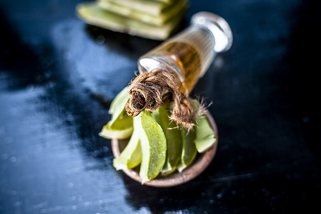Medicinal and floral essence of Ayurvedic herb Aloe vera with its leaves in a transparent bottle on wooden surface used in many Ayurvedic, Homeopathic, Modern and in Aromatherapyâs medicine.の写真素材