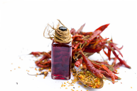 Close up of dried red chilies with its extracted oil in a transparent bottle isolated on white with chili flakes.の写真素材