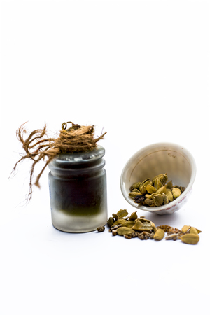 Green colored dry fruit essence of Green cardamom or elaichi isolated on white in transparent bottle.の写真素材