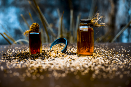 Effective and faithful home remedy for earache i.e. sesame seeds oil with clove oil. Raw sesame seeds and cloves on wooden surface.の写真素材