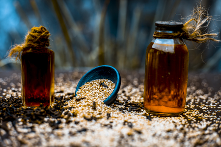 Effective and faithful home remedy for earache i.e. sesame seeds oil with clove oil. Raw sesame seeds and cloves on wooden surface.の写真素材