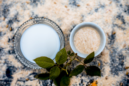 Close up of ayurvedic face pack of oats and milk only on wooden surface with milk and raw oats with some wheat grains and rose petals used to clean acne prone skin of all types.の写真素材