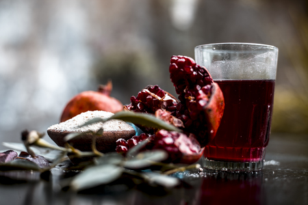Herbal and organic face pack of pomegranate with some ground or powdered oats to revitalize skin on wooden surface with pomegranate seed juice and some rose petals and leaves.の写真素材