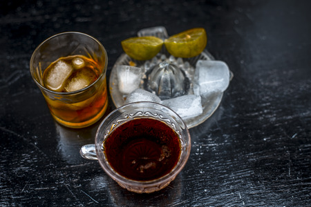 Close up of hangover remedy i.e. lemon juice and black tea in a transparent cup on wooden surface...