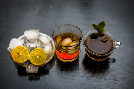 Close up of hangover remedy i.e. lemon juice and black tea in a transparent cup on wooden surface with Scotch or Scotch whiskey or Grain whiskey.の写真素材