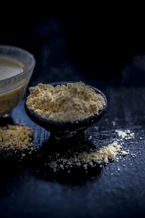 Close up of herbal remedy for hair related problems mainly hair fall on wooden surface i.e. Gram flour with curd and water in a glass bowl with raw powder of gram.の写真素材