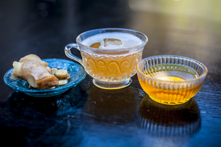 Iced tea of ginger and honey on wooden surface in a transparent cup with raw honey and ginger.Close up shot.の写真素材