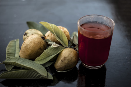 Close up of organic juice of red guava or amarood or jamrukh in a transparent glass with raw guava...