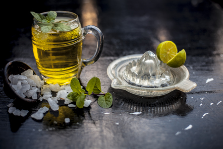 Close up of refreshing mint and lemon cooler in a transparent glass on wooden surface with raw lemon and juice and sugar.の写真素材
