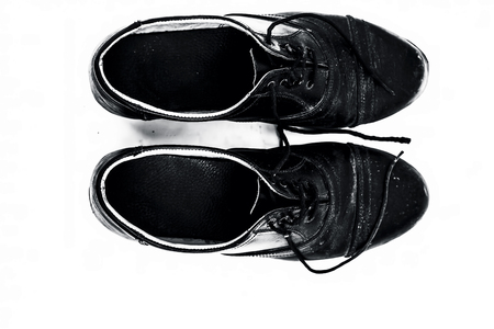Close up of small black colored school shoes isolated on white.の写真素材