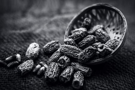 Close up of dried dates of kharek or Phoenix dactylifera in a fruit basket on brown surface.;の写真素材