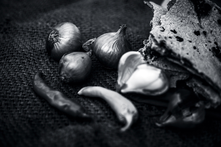 Close up of meal or lunch of villager or a typical farmer on gunny bag's background consisting of pearl millet's roti or chapati or bajra or bajri ki roti with some onions and chilies with it.の写真素材