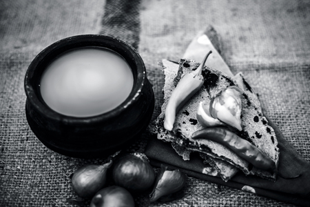 Close up of meal or lunch of villager or a typical farmer on gunny bag's background consisting of pearl millet's roti or chapati or bajra or bajri ki roti with some onions and chilies, buttermilk .の写真素材