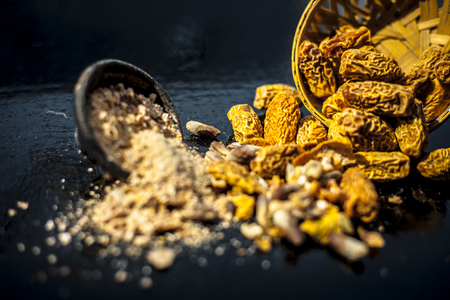 Close up of Dried dates or kharek or sukhi khajoor in a hamper with its powder on wooden surface.