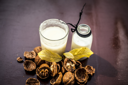 Close up of akhrot ka dudh or walnut milk on wooden surface with raw milk in  a glass bottle and some walnut in shellの写真素材
