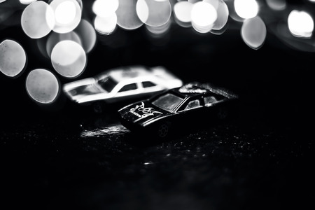 Close up of Black and white colored two miniature cars or toy cars on wooden surface with blurred background or bokeh or colorful lights of Christmas.の写真素材