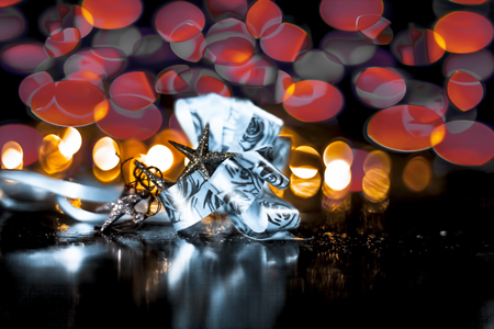 Close up of decoration of Christmas on wooden surface with blurred bokeh of colorful Christmas lights with it.の写真素材