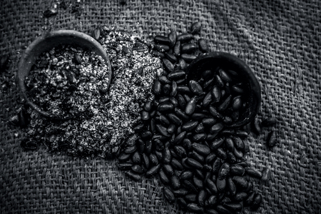 Close up of brown colored dried custard apples or sitaphal or sugar apple seeds in a black colored clay bowl and its powder of grounded seeds in a brown colored clay bowl.の写真素材