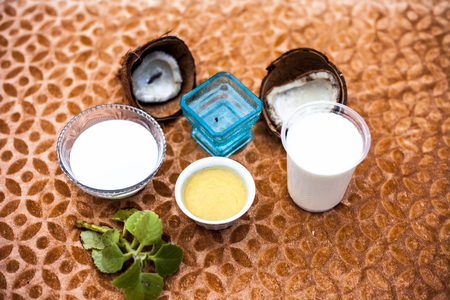 Close up of hair remedy to nourish hair naturally on brown colored fabric surface i.e. Coconut milk with curd mixed well along with some fresh leaves of ajwain plant for decoration.の写真素材