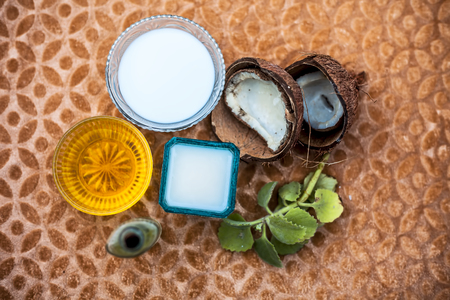 Hair therapy or hair growth remedy on wooden surface in a glass bowl consisting of coconut milk well mixed with honey and olive oil with raw ingredients also.の写真素材