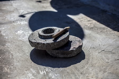 Close up of hand grinding stone or hand grinder or old motor or pestle or grain mills on rough surface still used in some of the villages of Asia and India.の写真素材