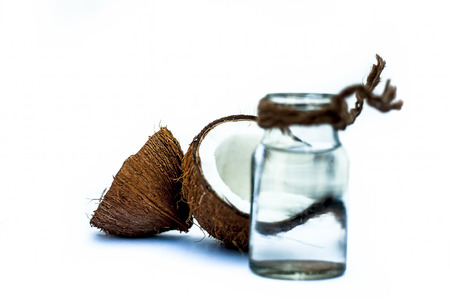 Raw organic coconut with its extracted fresh water in a white transparent glass bottle isolated on white.の写真素材