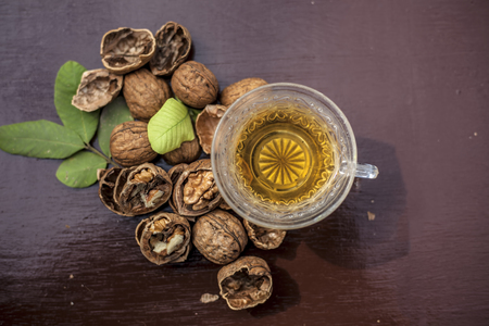 Close up of herbal organic tea of wall nut or walnut tea in a transparent glass cup with raw wall nut in shell and broken also.の写真素材
