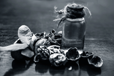 Close up of herbal organic extracted walnut oil in a transparent glass bottle with raw wall nuts on wooden surface.の写真素材