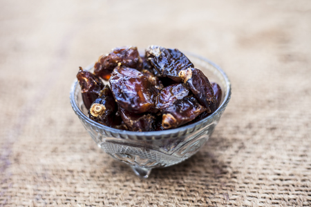 Close up of shot of raw organic dates or khajoor or Phoenix dactylifera in a glass bowl on a gunny bag background.の写真素材