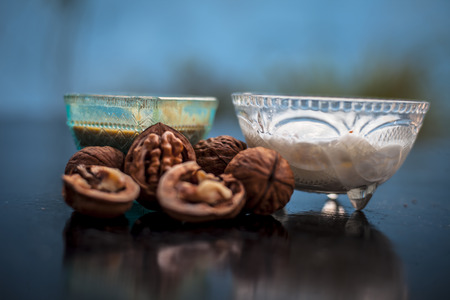 Close up of walnut face pack to prevent hair damage on wooden surface i.e. walnut powder well mixed with curd in a glass bowl with entire raw ingredients.の写真素材