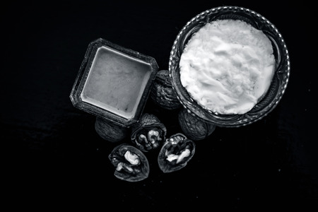 Close up of walnut face pack to prevent hair damage on wooden surface i.e. walnut powder well mixed with curd in a glass bowl with entire raw ingredients.の写真素材