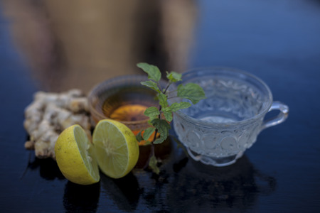 Close up of herbal green tea consisting of whiskey, ginger,honey,water,lemon and mint in a transparent cup on wooden surface.の写真素材