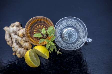 Close up of herbal green tea consisting of whiskey, ginger,honey,water,lemon and mint in a transparent cup on wooden surface.の写真素材