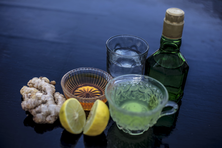 Close up of herbal green tea consisting of whiskey, ginger,honey,water,lemon and mint in a transparent cup on wooden surface.の写真素材