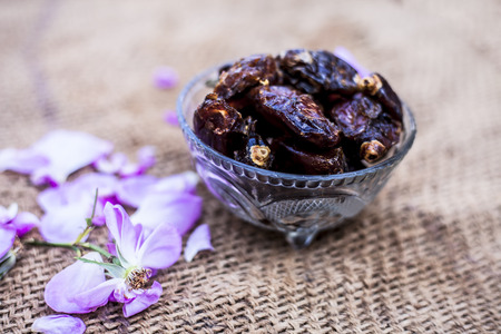 Close up of shot of raw organic dates or khajoor or Phoenix dactylifera in a glass bowl on a gunny bag background.の写真素材