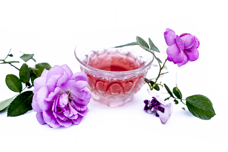 Close up view of organic fresh rose tea in a transparent glass cup isolated on white with raw roses.の写真素材