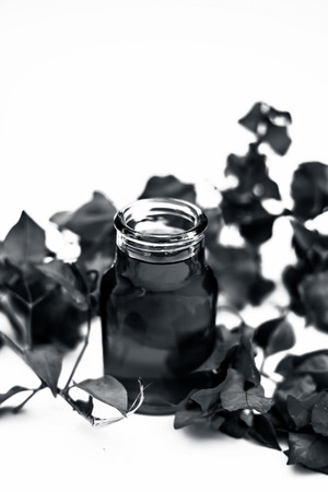 Close up shot of organic extracted oil of Bougainvillea isolated on white in a transparent glass bottle along with raw flowers.の写真素材