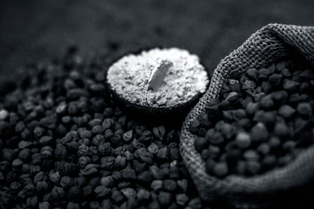 Close up of a jut bag full of chickpeas or grams in it and its floor or besan ka atta in a clay bowl on brown colored surface.の写真素材