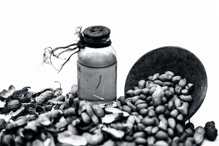 Close up of raw organic peanuts or ground nuts isolated on white along with its herbal organic extracted oil in a transparent bottle.の写真素材