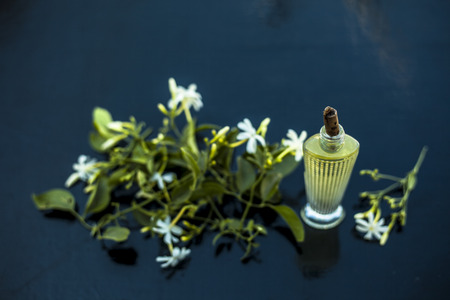 Close up of spray or perfume of Indian jasmine flower or juhi or Jasminum Auriculatum on wooden surface in a small bottle with raw flowers.の写真素材