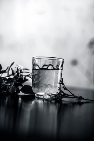 Close up of extract of Indian jasmine flower or juhi or Jasminum Auriculatum on wooden surface in a transparent glass with raw flowers.の写真素材