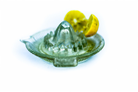 Blue colored glass juicer isolated on white along with some lemon juice extracted in it.の写真素材