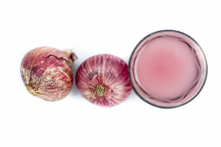 Close up of fresh organic herbal extracted Onion juice in a glass with raw onions or Allium cepa isolated on white.の写真素材