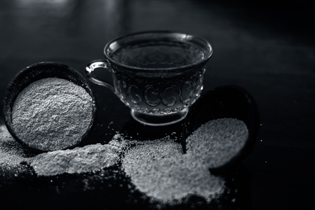 Clay bowl on wooden surface full of Poppy seeds or khus or opium poppy or bread seed poppy with its extracted herbal and organic plus beneficial detoxifying drink or tea in a transparent glass cup.の写真素材