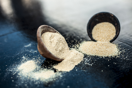 Close up of clay bowl on wooden surface full of Poppy seeds or khus or opium poppy or breadseed poppy with its powder in a clay bowl.の写真素材